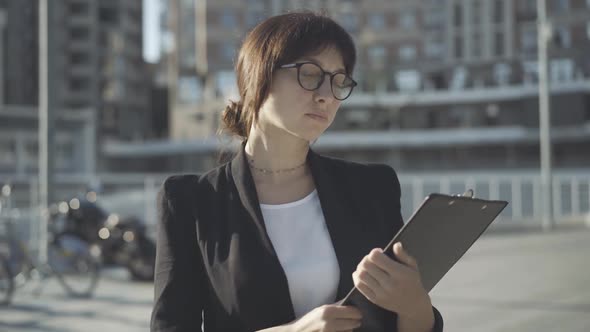 Portrait of Confident Successful Woman in Eyeglasses Standing on Sunny City Street and Looking at