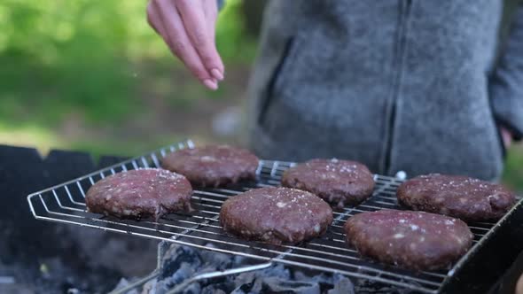 Salting Beef Burgers Cutlets Roasting on the Charcoal Barbecue Grill
