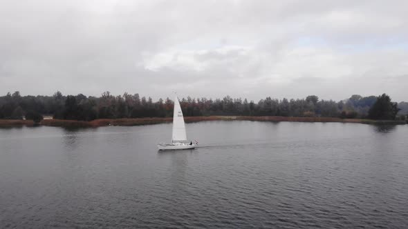 Dutch sailings vessel navigate on a fairway on a cloudy autumn day in Flevoland. Pan drone shot