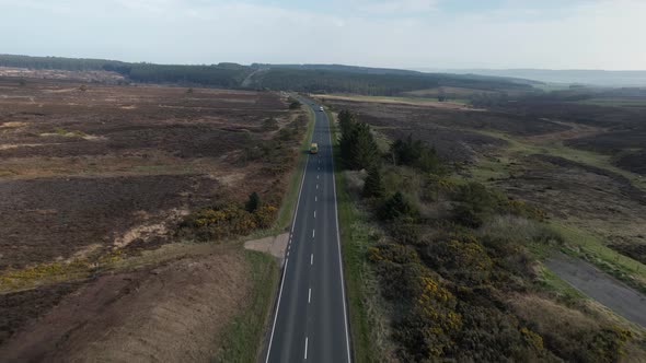 Aerial of alone bus driving in the street of Goathland - North York Moors National Park UK. Long exp