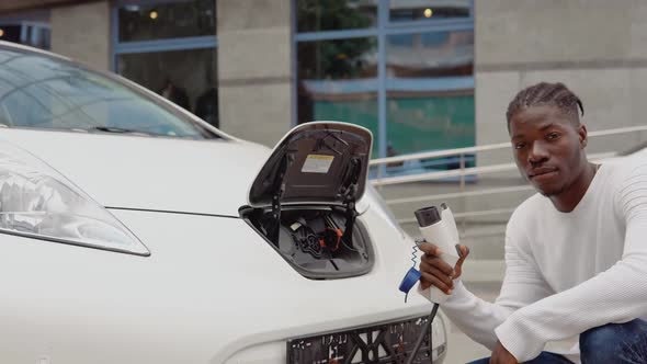 A Young African American Man Connects an Electric Car to the Charger