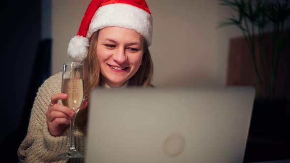 Woman in a Santa Hat Taking a Video Call on a Laptop with Friends