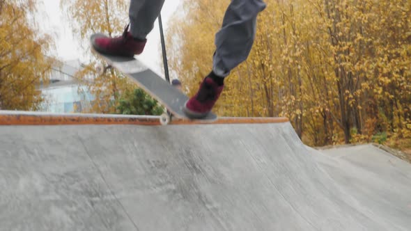 Skater Practicing in the Autumn Concrete Skate Park Making Tricks and Rides in Ramp