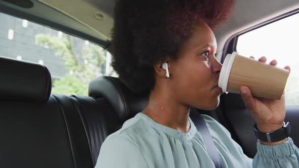 African american businesswoman drinking takeaway coffee in car