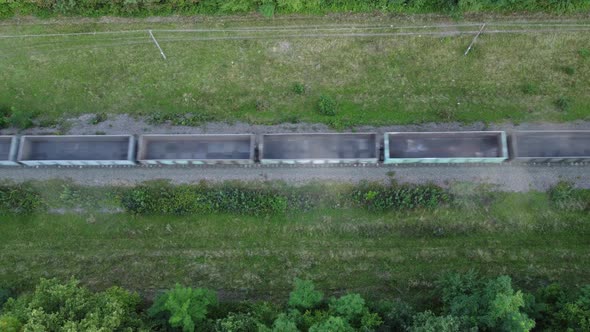 Aerial View of a Freight Train Carrying Empty Containers Driving Through a Forest Where There is