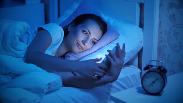 Woman Using His Mobile Phone in the Bed