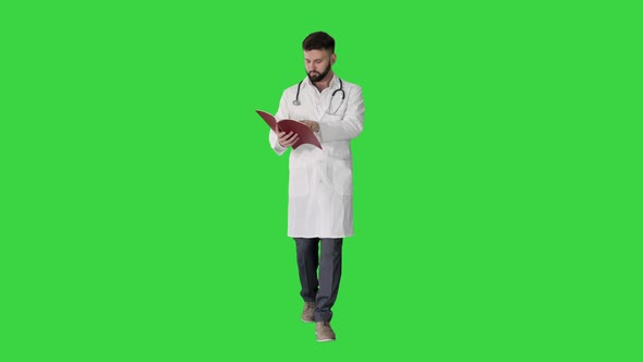 Doctor Reading a Book or a Journal While Walking on a Green Screen, Chroma Key.