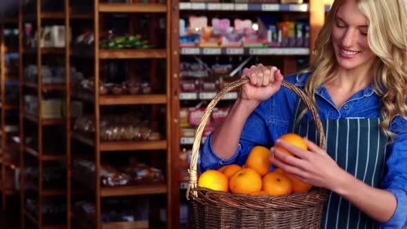 Smiling female staff holding basket of fruit in organic section