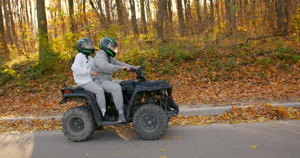 A Young Couple Rides an ATV Offroad in the Autumn Forest