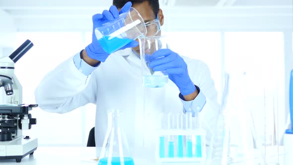 Research Scientist Pouring Chemical in Beaker for Reaction in Laboratory