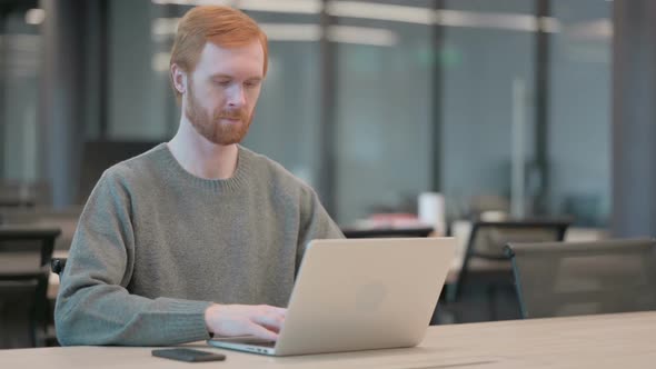 Young Man Showing Thumbs Up Sign While Using Laptop in Office