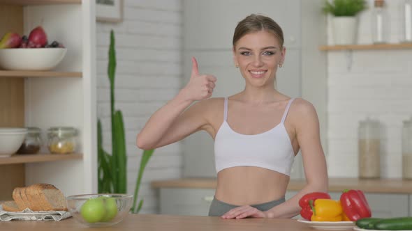Sporty Woman Showing Thumbs Up While Standing in Kitchen