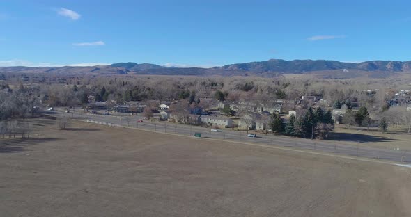 Fort Collins Colorado drone flight facing the rocky mountains on a blue sky and hazy warm morning in