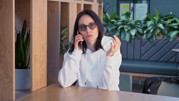 A Woman Speaks on a Mobile Phone in a Cozy Coffee Shop