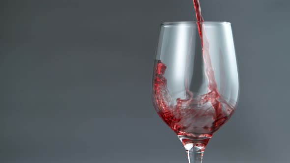 Pouring Red Wine in Super Slow Motion on Grey Background.