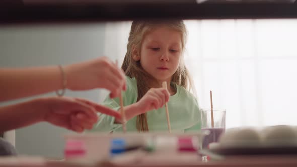 Concentrated Little Girl with Mother Draws Marbling Patterns