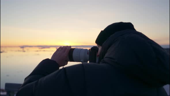 Photographer Focussing Long Lens Of Camera To Shoot Sunset