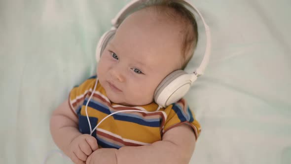 Top Down View of Adorable Toddler Laying on Blanket with Headphones on Head