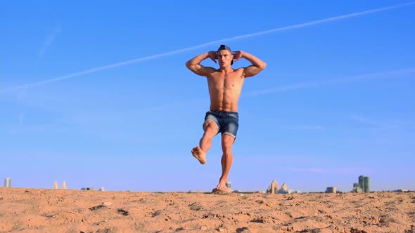 Young Fit Man Doing Sports Exercises at the Beach  Squatting on One Leg