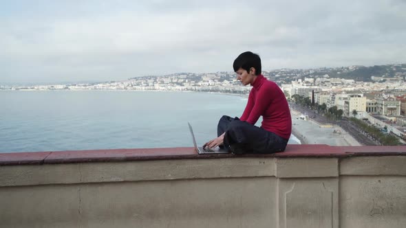 Young Woman Intently Typing on the Computer Outdoor