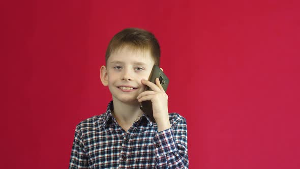 Caucasian boy 8 years old talking on the phone, nodding his head in agreement. studio shooting on a 