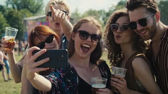 Group of caucasian friends making funny faces for a common selfie on music festival. Shot with RED h