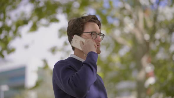 Bearded Man in Eyeglasses Talking By Smartphone Outdoor