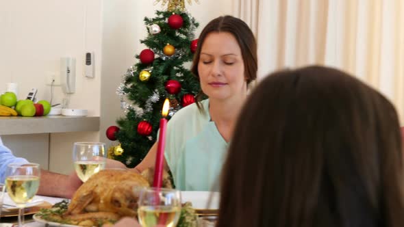 Extended family saying grace before christmas dinner