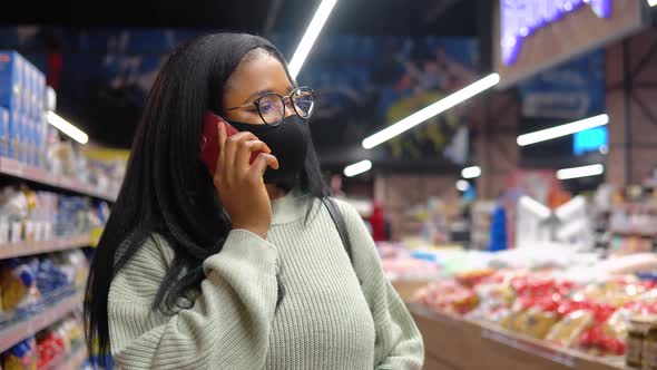 Girl in a Mask Talking on the Phone in the Supermarket