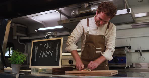 Caucasian male chef working inside food truck preparing dinner food - Summer job concept