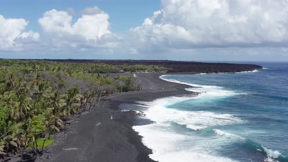 Close-up aerial shot flying over a newly formed black sand beach on the coast of the Big Island of H