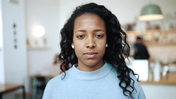 Happy brunette African woman wearing blue sweater opening eyes at the camera