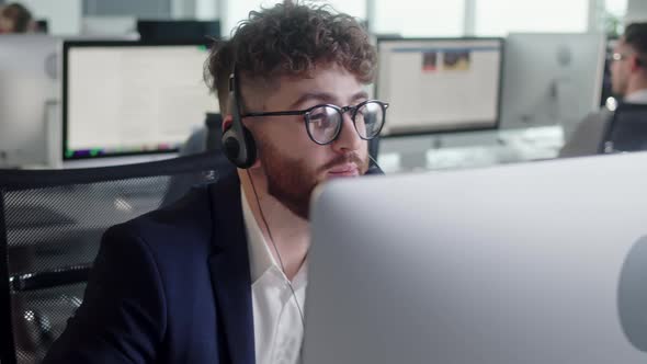 Close Up Portrait of a Technical Customer Support Specialist Talking on a Headset While Working on a