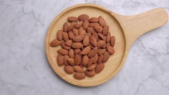 Top view falling almonds nuts into a wooden bowl, Slow motion.