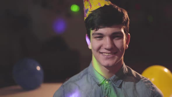 Portrait of Smiling Young Man in Birthday Hat Looking in the Camera