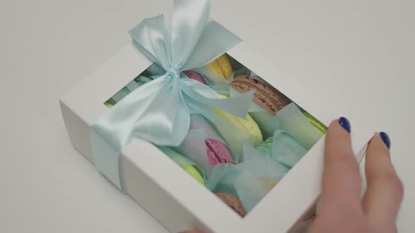 Woman's Hands Pushing Gift Box with Macaron Cookies