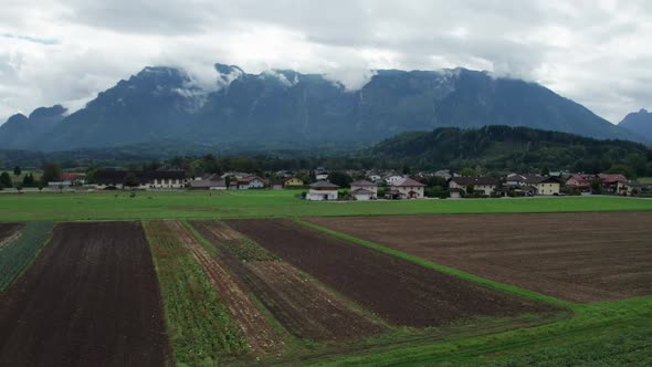 Aerial View of Green Agricultural Fields in Austria Near the Mountains in Clouds