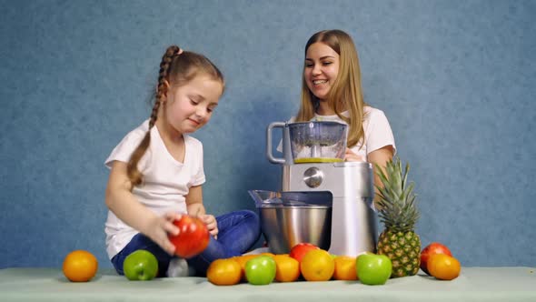 Beautiful smiling girl with fruits and blender near table