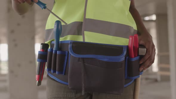 Builder Putting Screwdriver in Waist Bag