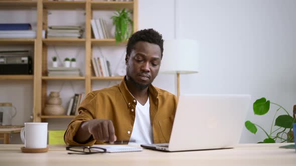 African Man Use Laptop Look at Screen and Write Note in Notebook with Pen Spbas