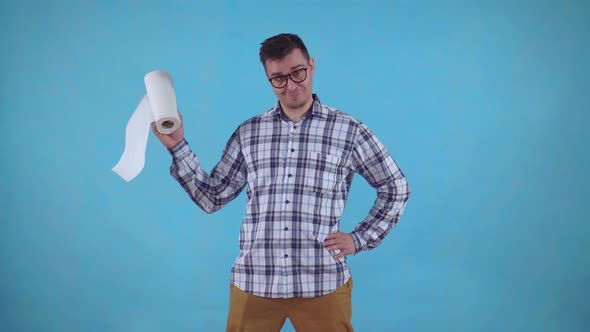 Positive Young Man Standing on a Blue Background and Holding Paper Towels