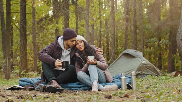 Young Hispanic Married Couple Tourists Rest in Woods Camping Man and Woman in Love Drinking Hot Tea