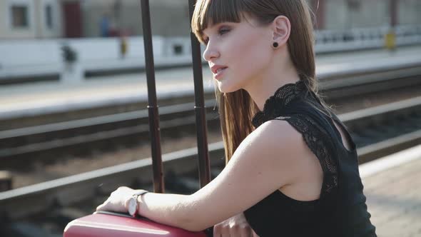 Portrait of Attractive Girl Looks Around on Railway Station and Smiles Gently