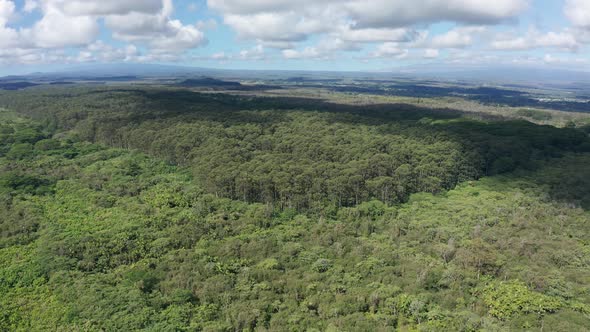 Reverse pullback aerial shot of both Mauna Loa and Mauna Kea volcanoes with clouds covering their su