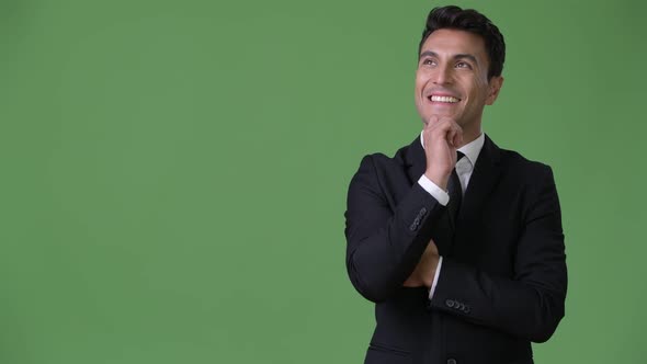 Young Handsome Hispanic Businessman Against Green Background