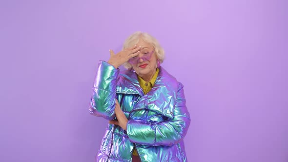 Cute Smiling Old Lady Bought New Fashionable Clothes, Isolated Purple Background in the Studio