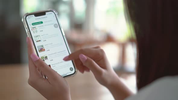 Young girl in with mobile phone in hands chooses fast food in an online store to place an orders 