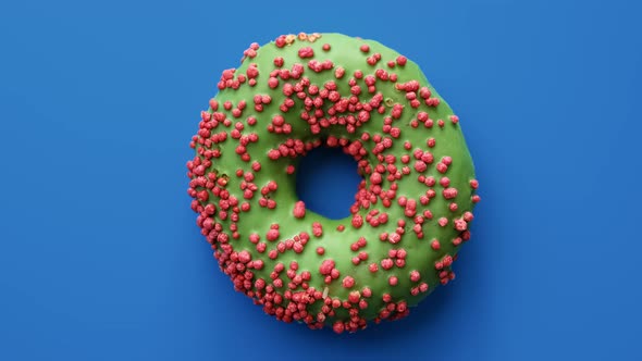 Slowly Rotating Fresh Appetizing Fried Baking Doughnut Covering By Green Icing Isolated on Blue