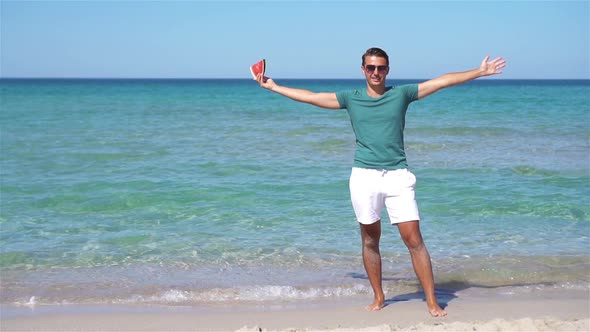 Happy Man Having Fun on the Beach and Eating Watermelon