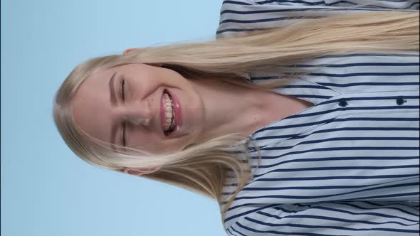 Happy Young Lady Bursting in Laughter on Blue Background